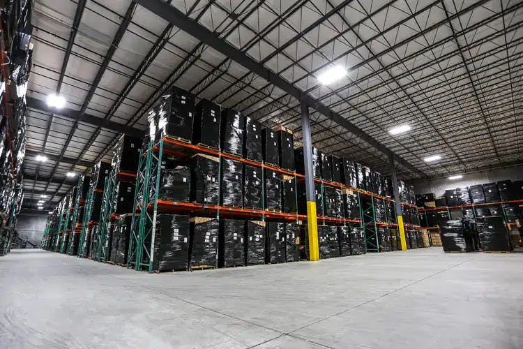 Wide angle shot of the Skar Audio warehouse with pallets stacked in 3 levels of shelves